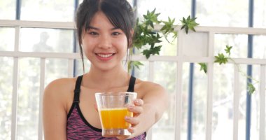 Kadın elleri soğuk portakal suyu tutuyor taze meyve suyu içiyor. Asyalı kadınlar güler, kameralı sağlık hizmetleri yaşam tarzına bakarlar. Güzel bir kadın kokteyl şişesinden portakal suyu dolduruyor.