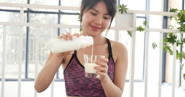 Women hands holding white glass of milk pouring from bottle. Asian women smile laugh look at camera health care home fitness lifestyle. Beautiful female drinking fresh milk low-fat dairy free lactose