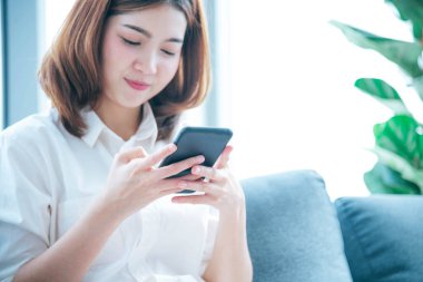 İnternet sitesi Reading Online Article, Blog, vlog ile akıllı telefon tutan Asyalı bir kadın. Genç kadının elleri telefon teknolojisi yaşam tarzını tutuyor. Mutlu Kadın dijital akıllı telefon kullanıyor