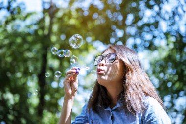 Neşeli sabun üfleyen mutlu kadın açık havada yeşil park. Asyalı genç kadınlar eğlence baloncuğu, özgürlük yaşam tarzı. Gevşemekten hoşlanan güzel bir kız. Mutlu yüzlü güzel bir kadın oyunu