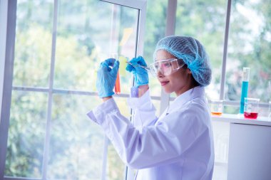 Asian Woman scientist hand write note research in medical lab look at science microscope medical test. Researcher biology chemistry. Asian Female technician laboratory using microscope blood test