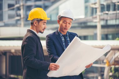 İnşaat mühendisi takımları modern kentteki inşaat sahasında birlikte çalışan işçi kaskı takıyorlar. Foreman Endüstri Mühendislik Mühendisliği ekip çalışması. Asya endüstrisi profesyonel takımı