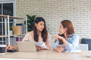 İki iş kadını takım toplantısı şirket masasında dizüstü bilgisayarla yapılıyor. Finansal grafik grafikleri okuyan iki genç kadın pazarlama verilerini analiz etmeyi planlıyor. Asyalı ekip çalışma bürosu.