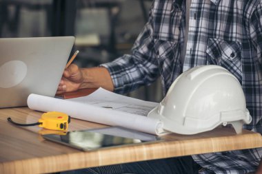 Asyalı mühendis inşaat inşaat müteahhiti kamu çalışanı ortakları toplantı alanında beyin fırtınası yapıyor. Tasarım mühendisi, işçi kaskı masanın üstünde. Mühendis ekip çalışması danışmanlığı