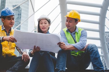 İnşaat mühendisi takımları el sıkışırken inşaat alanında kask takıyor. Foreman Endüstri Projesi Mühendis ekip çalışması. İki Asyalı mühendis takımı el sıkışıyor.