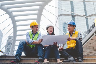 İnşaat mühendisi takımları modern kentteki inşaat sahasında birlikte çalışan işçi kaskı takıyorlar. Foreman Endüstri Mühendislik Mühendisliği ekip çalışması. Asya endüstrisi profesyonel takımı