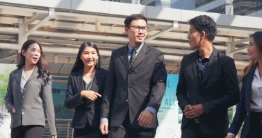 Group of business people asian team partners walking in city happy together. Leader executive men standing at modern urban city with confident teamwork. Portrait diversity businesspeople teamwork