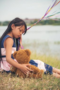 Yeşil Park 'ta oyuncak ayıya sarılırken mutlu çocuk. Oyuncak ayı, küçük çocuklar için en iyi arkadaş tatlı kız. Otizm mutlu bir şekilde oyun bahçesinde birlikte oynayarak mutlu bir aile sevgisi ve sıcacık kucaklaşmayı hisseder.