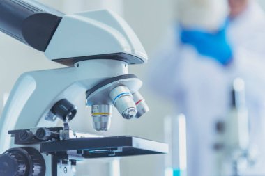 Biyoloji kimya laboratuvarında mikroskop ekipmanı. Laboratuvar masa mikrobiyolojisi ekipmanları üzerinde bilimsel deney mikroskobu. Laboratuvar arka planında kimya nesneleri. Kimya bilimsel kavramı