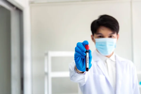 Scientist man holding sample blood test tube in science laboratory. Doctor clinic healthcare technician lab testing blood sample diagnosis. Asian man scientist working in hiv testing medical lab.