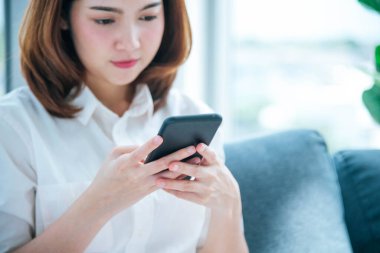 İnternet sitesi Reading Online Article, Blog, vlog ile akıllı telefon tutan Asyalı bir kadın. Genç kadının elleri telefon teknolojisi yaşam tarzını tutuyor. Mutlu Kadın dijital akıllı telefon kullanıyor