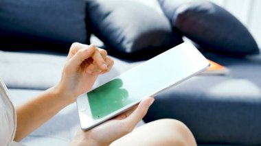 İnternetten dijital tablet alışverişi yapan Asyalı bir kadın arıyor, mesaj yolluyor, internet teknolojisi yaşam tarzında gülümsüyor. Asyalı kadın akıllı tablete dokunuyor mobil uygulama ev ofisini kullanarak ellere odaklanıyor.