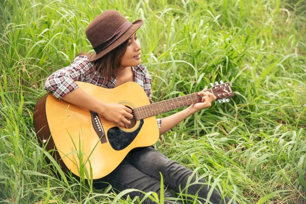 Young women playing acoustic guitar outdoor in green park. Woman person playing acoustic guitar music instrument at home, young Asian musician girl lifestyle in beautiful nature. Happy guitarist
