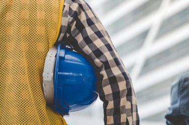 İnşaat mühendisi elleri inşaat mühendisliği için beyaz kaskı tutuyor. İnşaat mühendisi takım elbiseli adam inşaat sahasında beyaz kasklı kaskı elinde tutuyor.