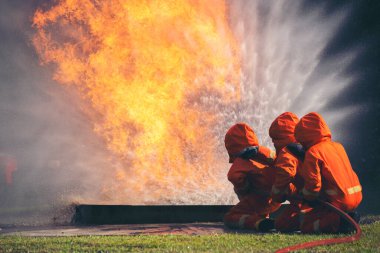 Firefighter Rescue training in fire fighting extinguisher. Firefighter fighting with flame using fire hose chemical water foam spray engine. Fireman wear hard hat, safety suit uniform for protection