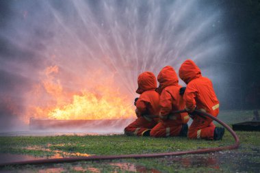 Firefighter Rescue training in fire fighting extinguisher. Firefighter fighting with flame using fire hose chemical water foam spray engine. Fireman wear hard hat, safety suit uniform for protection