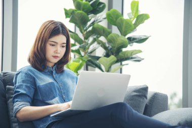 Ev ofisinde bilgisayarla bilgisayar kullanarak çalışan Asyalı kadının mutluluğu. Keyfine bak Asyalı iş kadını klavye yazıyor dizüstü bilgisayar kullanıyor gülümsüyor, ev ofisine gülüyor..