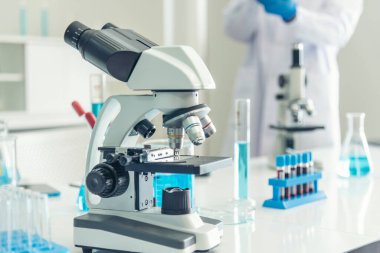 Biyoloji kimya laboratuvarında mikroskop ekipmanı. Laboratuvar masa mikrobiyolojisi ekipmanları üzerinde bilimsel deney mikroskobu. Laboratuvar arka planında kimya nesneleri. Kimya bilimsel kavramı