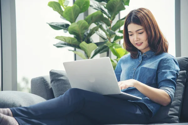 Happiness Asian Woman working from home using laptop online meeting in home office. Happy relax time asian business woman typing keyboard use notebook laptop Smiling, laughing at home office.