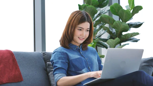Asian Female freelance using laptop at home office desk. Woman reading financial graph chart Planning analyzing marketing data. Asian female people working office firm with business stuff, coffee cup