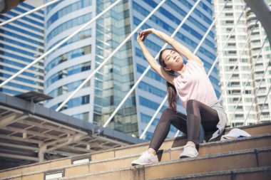 Modern şehirde vücut egzersizi yapan spor jimnastiği yapan kadın spor kıyafetlerini dışarıda giyer. Dışarıda güneşli bir havada egzersiz yapan genç bir kadın. Sağlıklı sağlık yaşam tarzı kadın konsepti.