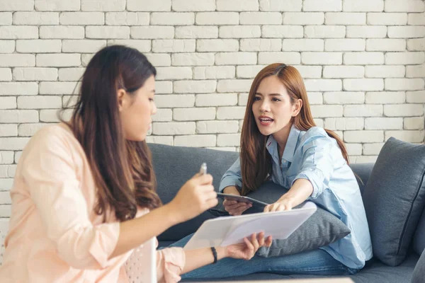 Two asian Female freelance reading financial graph charts Planning analyzing marketing data. Asian people team working office firm. Two businesswomen team meeting using laptop at company office desk.
