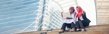 Banner Arab team hold laptop uae union teamwork people. Panorama arab group of arabian people using laptop look at screen happiness in muslim UAE city. West asian people teams meeting with copy space