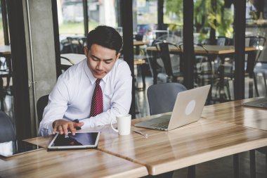 İşadamı internet üzerinden çalışan kablosuz internet teknolojisiyle ofis masasında akıllı dijital tablet kullanıyor. Asyalı yakışıklı adam akıllı tablet kullan, cihaz kontrolü yap. Serbest iş adamı teknolojisi