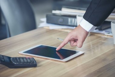 İnternetteki konferansta çalışan kablosuz internet teknolojisi aracılığıyla ofis masasındaki akıllı dijital tableti kapat. Elinde akıllı tablet telefon aleti tutan bir adam. Çok zeki bir iş adamı.