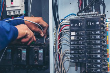 Elektrik teknisyeni elektrik kablosunu kontrol etti. Müfettişler santralde çalışan makine bakım servisini teslim etti. Elektrikçi devre onarım voltajı. Erkek eli şalteri tamir eder