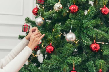 Kadın elleri Noel ağacını süslüyor kırmızı top, takı, kar taneciği. Asyalı kadın dekorasyon balosu balosu Noel ağacı, Noel bayramı kış mevsimsel kutlaması. Gümüş yıldız madalyasını tutan elleri kapatın.