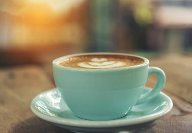 Sütlü, ahşap masadaki Latte sanat kahve fincanı. Espresso shot 'la sütlü kahve fincanı yapılır. İtalyan kafeteryasında sütlü kapuçino. Kafeteryada fotokopi alanı olan kahverengi kahve içeceği.