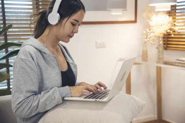 Ev ofisinde bilgisayarla bilgisayar kullanarak çalışan Asyalı kadının mutluluğu. Keyfine bak Asyalı iş kadını klavye yazıyor dizüstü bilgisayar kullanıyor gülümsüyor, ev ofisine gülüyor..