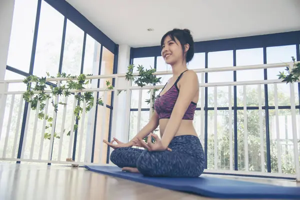 Asana yoga Beautiful woman smiling in sportswear sitting on yoga mat home fitness happy wellness lifestyle. Smiling asian woman doing asana yoga body, leg stretching in living room home fitness sport
