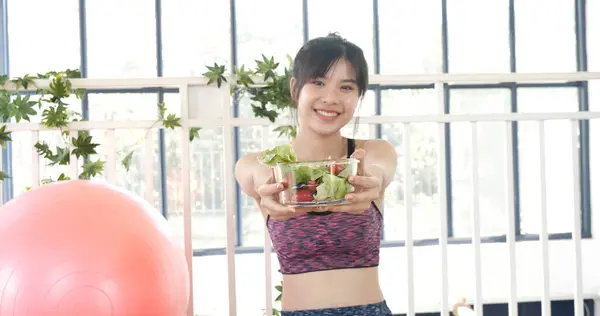 Healthy woman workout holding organic salad bowl healthy lifestyle. Wellness Asian women dressing organic green salad tomato vegetable dish. Beautiful girl healthcare vegan wellness lifestyle concept