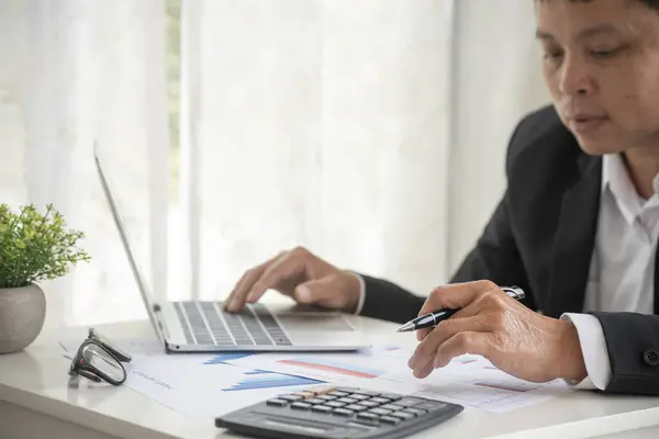 Asian businessman hands calculating number, graph, chart audit planning accountancy on business report. Asian professional Business man hands using calculator counting tax financial bill. Tax audit Finacial concept.