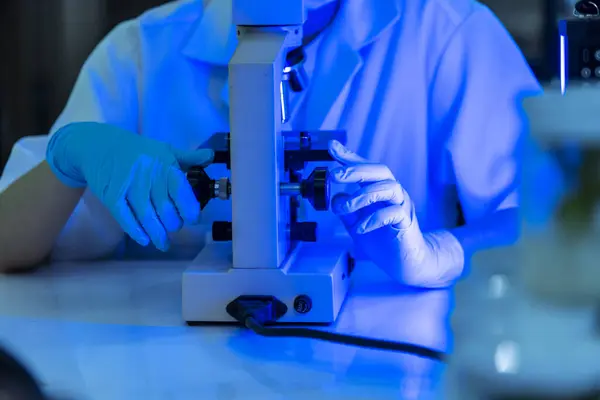 Female technician laboratory analyze genetic research. Woman scientist in lab look at science microscope medical test researching biology chemistry in blue light black background. Chemistry Medical