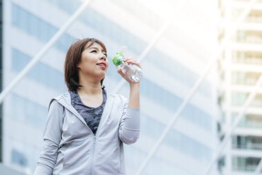 Modern şehirde su şişesi içen kadınlar spor kıyafetlerini dışarıda giyerler. Dışarıda güneşli bir havada egzersiz yapan genç bir kadın. Sağlıklı sağlık yaşam tarzı kadın konsepti