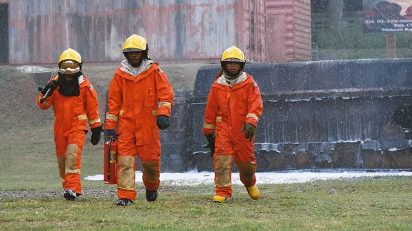 Firefighter Rescue team training in fire fighting extinguisher. Firefighter teamwork fighting with flame using fire hose chemical water foam spray engine. Fireman wear hard hat, safety suit uniform