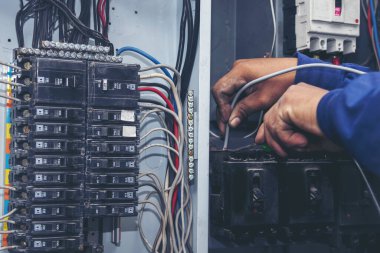 Müfettişler santralde çalışan makine bakım servisini teslim etti. Elektrik teknisyeni elektrik kablosunu kontrol etti. Elektrikçi devre onarım voltajı. Erkek eli şalteri tamir eder