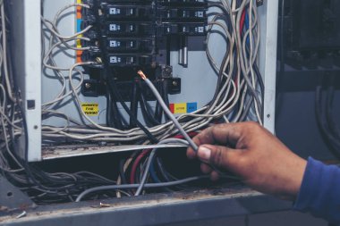 Müfettişler santralde çalışan makine bakım servisini teslim etti. Elektrik teknisyeni elektrik kablosunu kontrol etti. Elektrikçi devre onarım voltajı. Erkek eli şalteri tamir eder