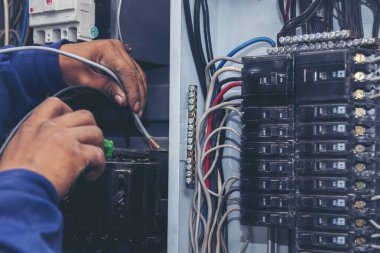 Müfettişler santralde çalışan makine bakım servisini teslim etti. Elektrik teknisyeni elektrik kablosunu kontrol etti. Elektrikçi devre onarım voltajı. Erkek eli şalteri tamir eder