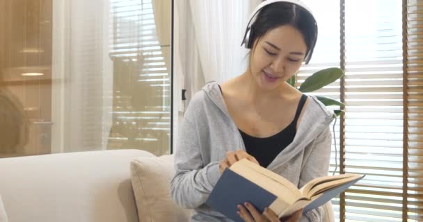 Šťastná Asijská Žena Používat Sluchátka Poslouchat Hudbu Čtení Knihy Sedí — Stock video