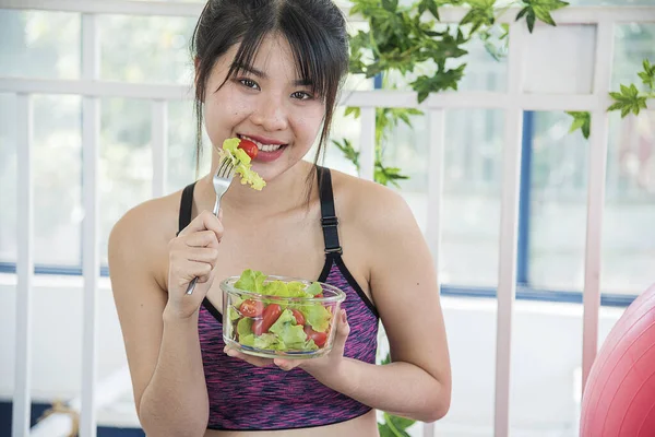 Wellness Asian women dressing organic green salad tomato vegetable dish. Beautiful girl healthcare vegan wellness lifestyle concept. Healthy woman workout holding organic salad bowl healthy lifestyle