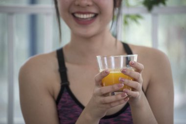 Kadın elleri soğuk portakal suyu tutuyor taze meyve suyu içiyor. Asyalı kadınlar güler, kameralı sağlık hizmetleri yaşam tarzına bakarlar. Güzel bir kadın kokteyl şişesinden portakal suyu dolduruyor.