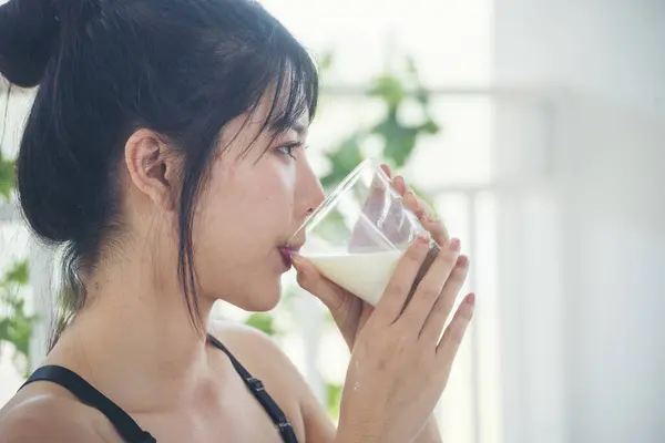Asian women smile laugh look at camera health care home fitness lifestyle. Beautiful female drinking fresh milk low-fat dairy free lactose. Women hands holding white glass of milk pouring from bottle
