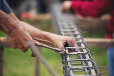 Kerpeten kullanan inşaat işçisi elleri demir tel kullanıyor. Açık hava işçisi, kerpeten kullanıyor, inşaat işlerinde çalışıyor. Erkekler elleri büküyor çelik telleri kesiyor beton işçiliğini destekliyor.