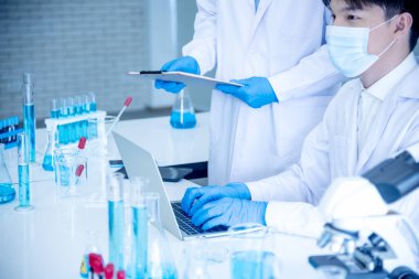 İki Asyalı bilim adamı kimya bilimi tüpü deney tüpü antikor örneğini kovid-19 virüsüne karşı laboratuvar geliştirmek için depoluyorlar. Kimya Laboratuarı 'nda bilim adamı danışmanı, analizi