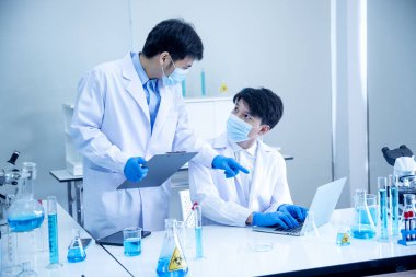 İki Asyalı bilim adamı kimya bilimi tüpü deney tüpü antikor örneğini kovid-19 virüsüne karşı laboratuvar geliştirmek için depoluyorlar. Kimya Laboratuarı 'nda bilim adamı danışmanı, analizi