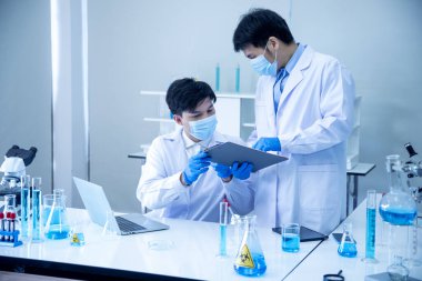 İki Asyalı bilim adamı kimya bilimi tüpü deney tüpü antikor örneğini kovid-19 virüsüne karşı laboratuvar geliştirmek için depoluyorlar. Kimya Laboratuarı 'nda bilim adamı danışmanı, analizi